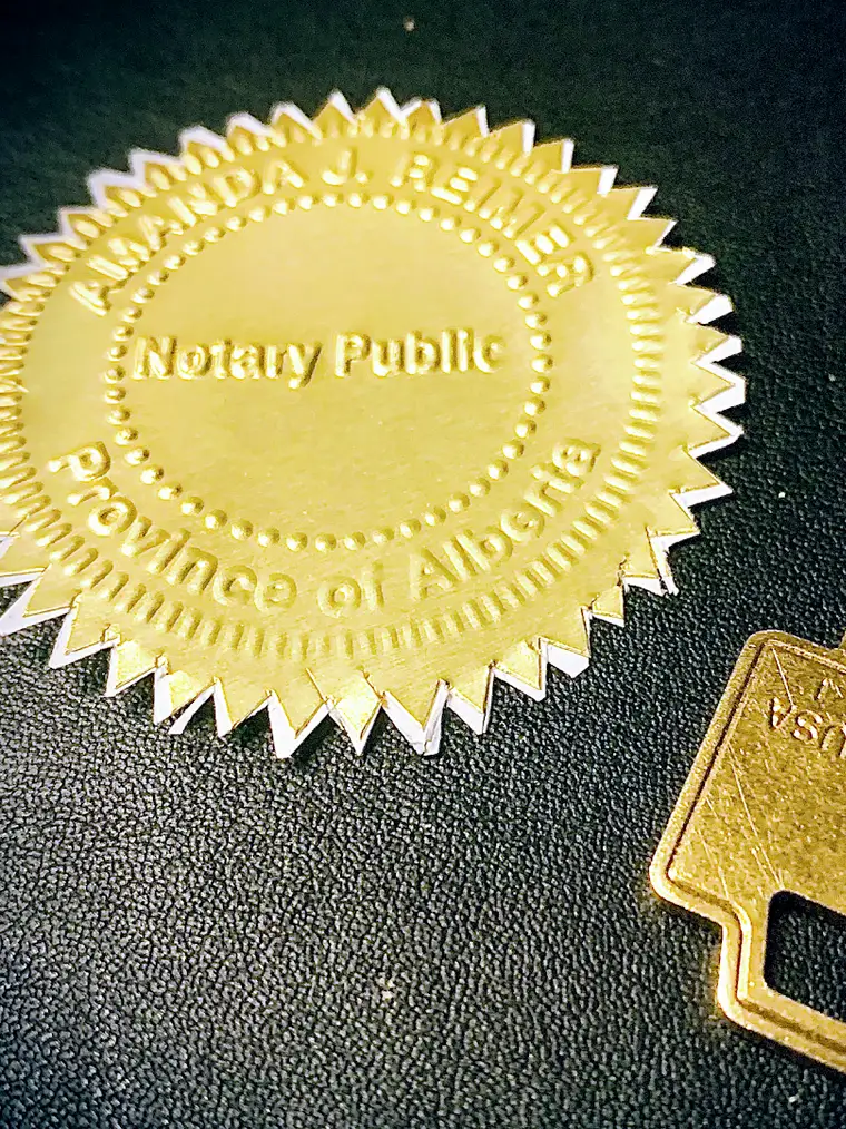 An embossed gold Notary Public seal for the Province of Alberta beside a brass key