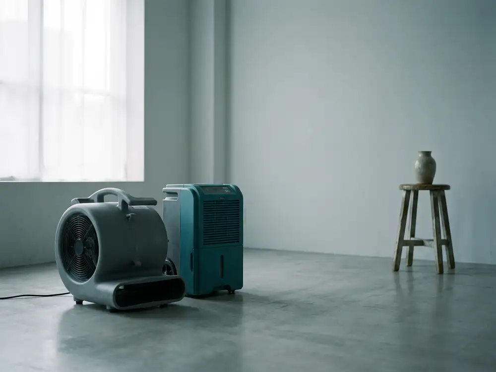 An air mover and dehumidifier standing on a clean floor in an empty room