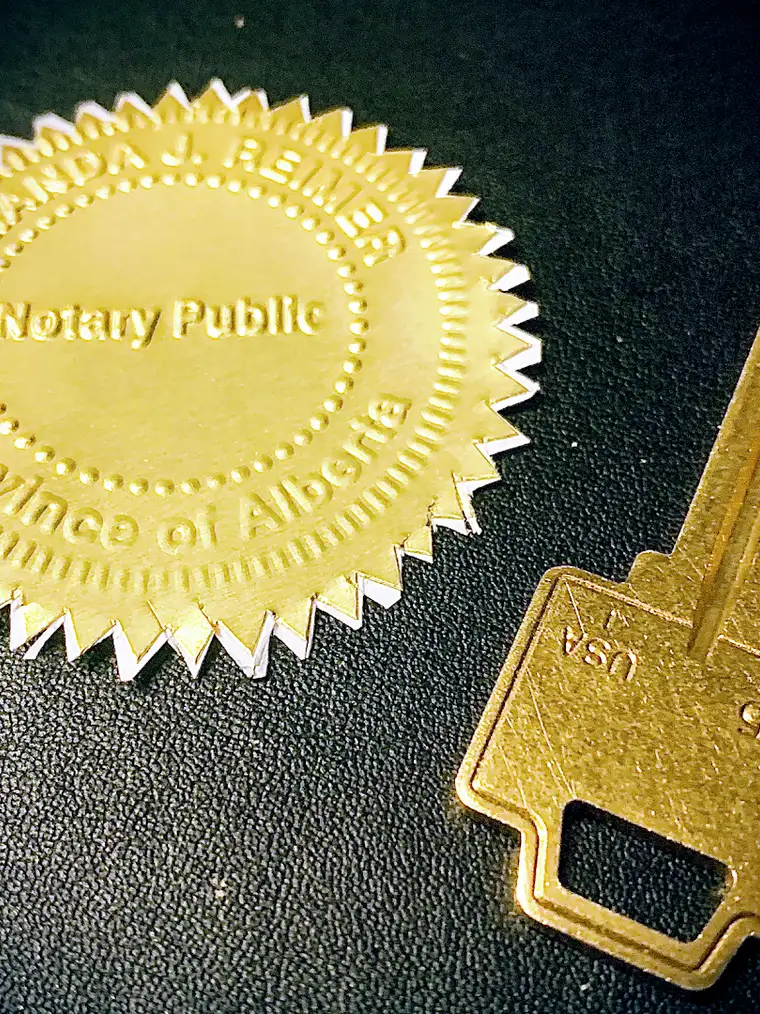 An embossed gold Notary Public seal beside a brass key