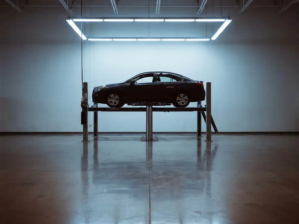 An automotive service bay with a vehicle raised on a hoist