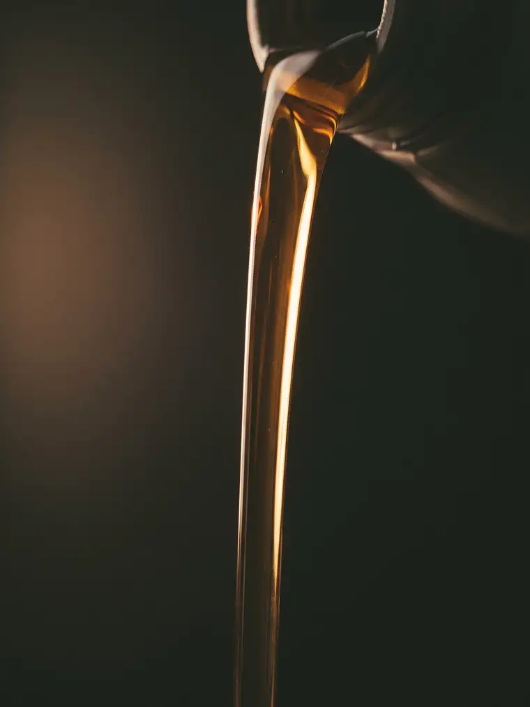 Motor oil pouring in a thin stream against a dark background