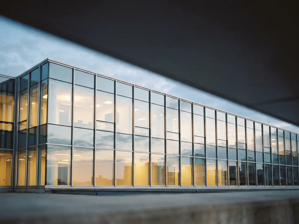A wall of architectural glass on a commercial building in the early evening